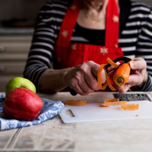 Henkilö kuorii porkkanaa tukevalla kuorimaveitsellä.