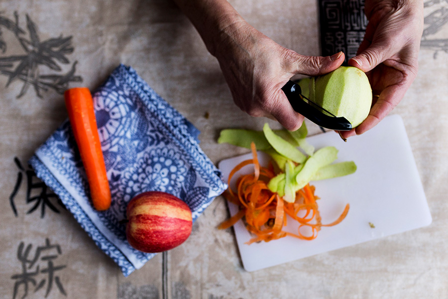 Kädet kuorimassa omenaa.