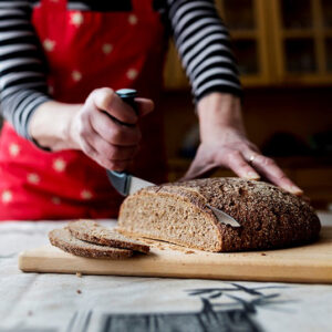 Henkilö leikkaa leipää pystykahvaisella veitsellä.