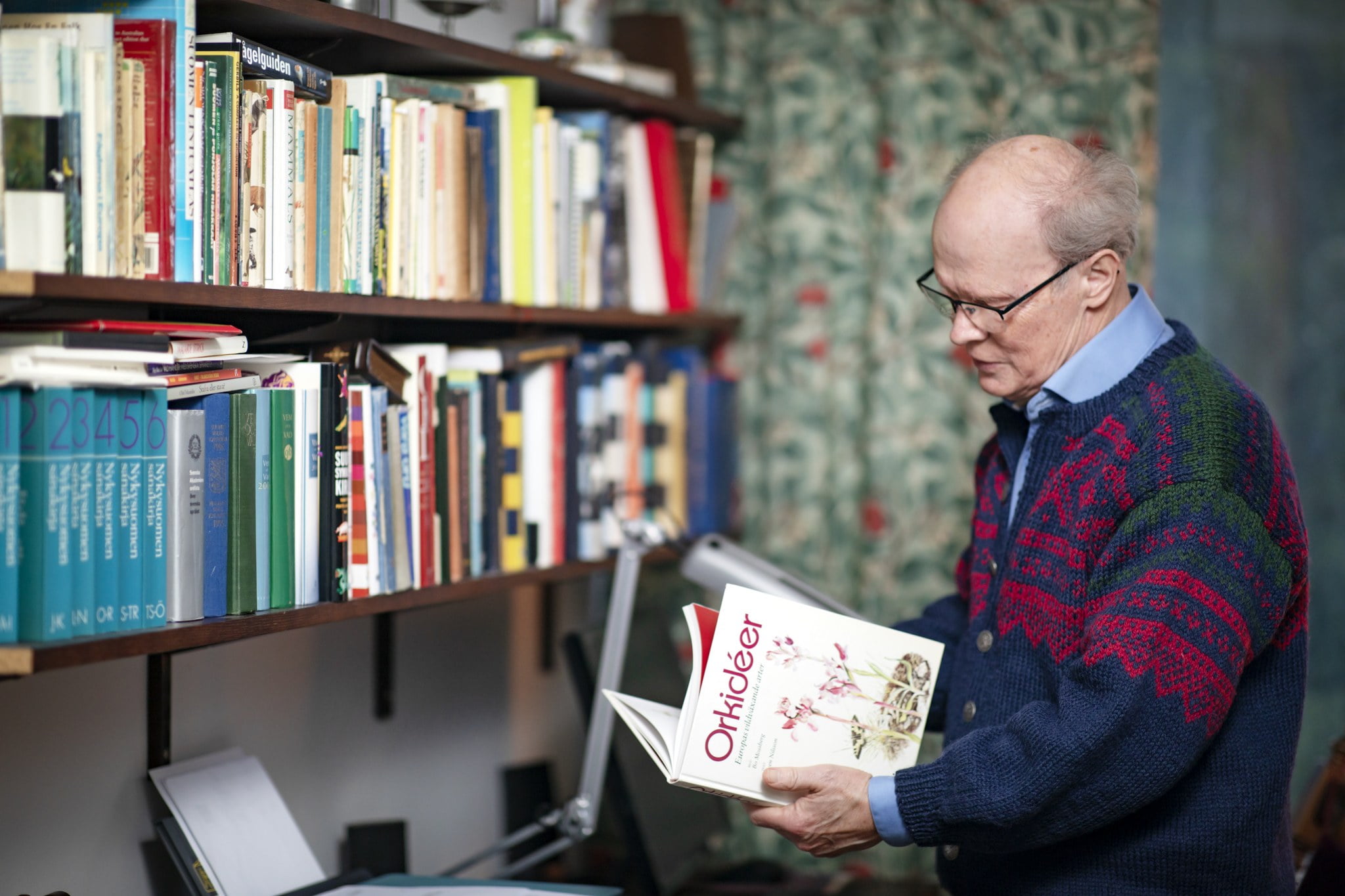 Tom Pettersson selailee orkideoista kertovaa ruotsinkielistä kirjaa