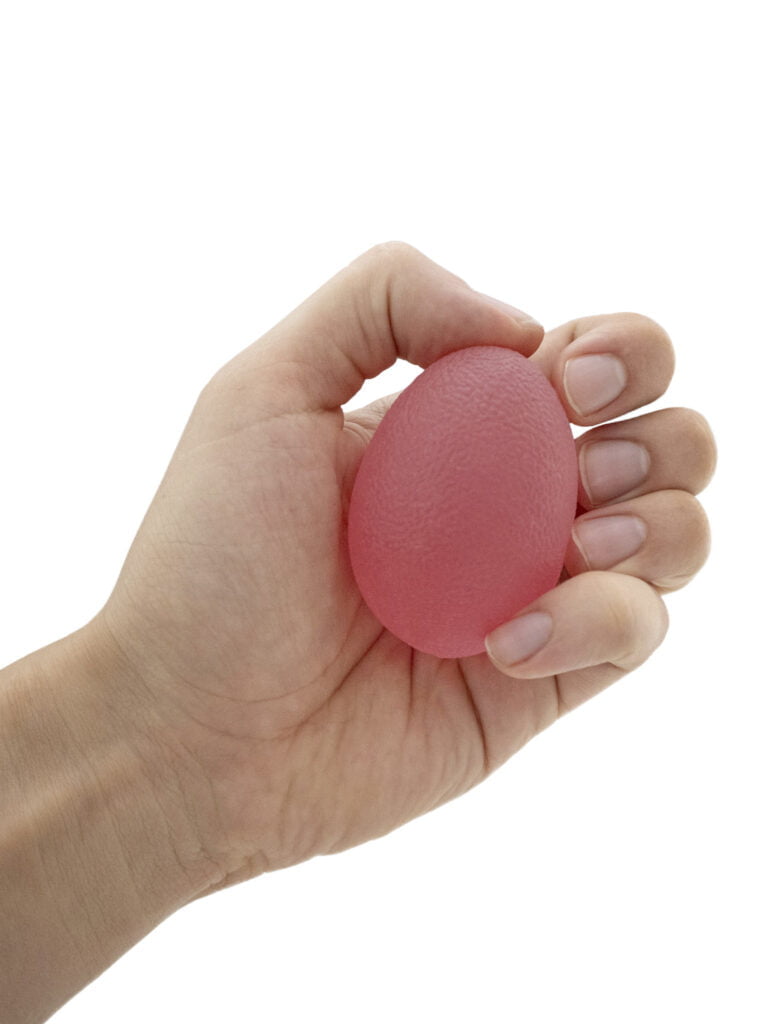 Käsiterapiapallo punainen kädessä.
