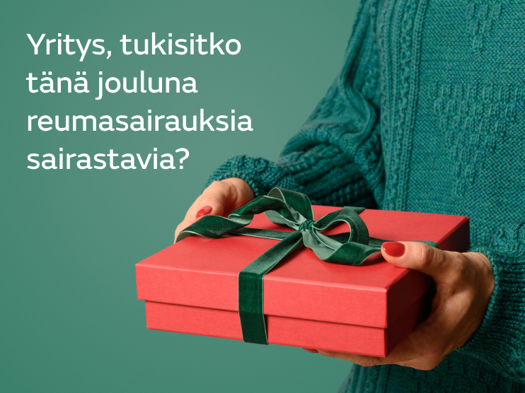 Henkilö vihreässä villapaidassa ojentaa lahjapakettia.