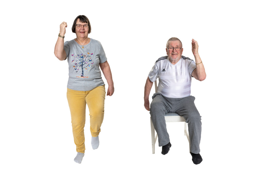 Kuvassa kaksi henkilöä tekee polvennostoja. Toinen seisten ja toinen tuolilla istuen.