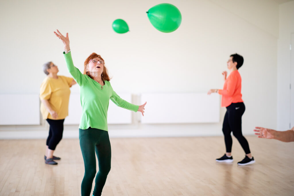Kuvassa kolme naisoletettu pomputtelee puhallettuja ilmapalloja.
