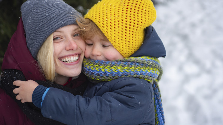 Nainen ja lapsi halaavat ulkona talvella.