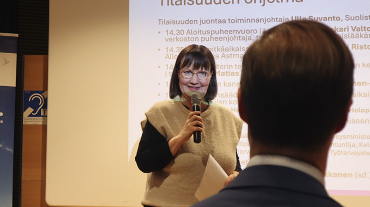 Nainen puhuu mikrofoniin.