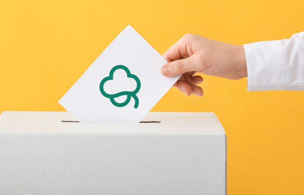 Käsi laittamassa lipuketta laatikkoon.